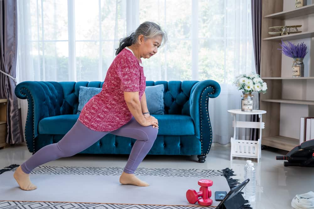 A senior woman practicing exercise on a mat in her home
