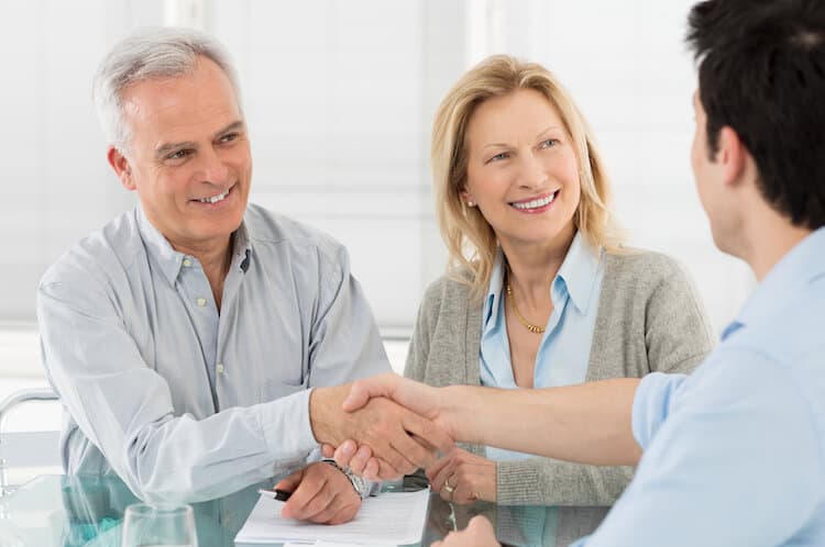 Senior couple shaking hands with a financial advisor.