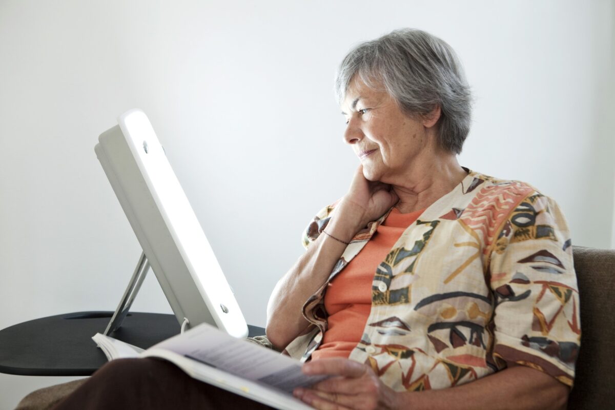 Senior woman reading while using light therapy