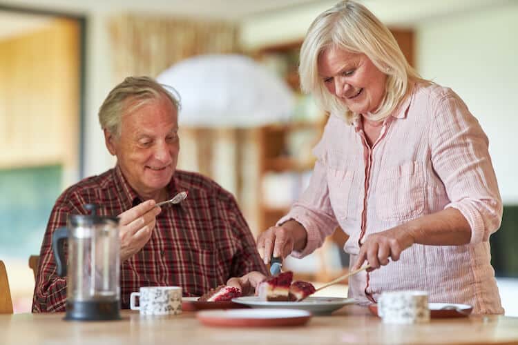A happy senior couple enjoying cake, happily secure in their home.