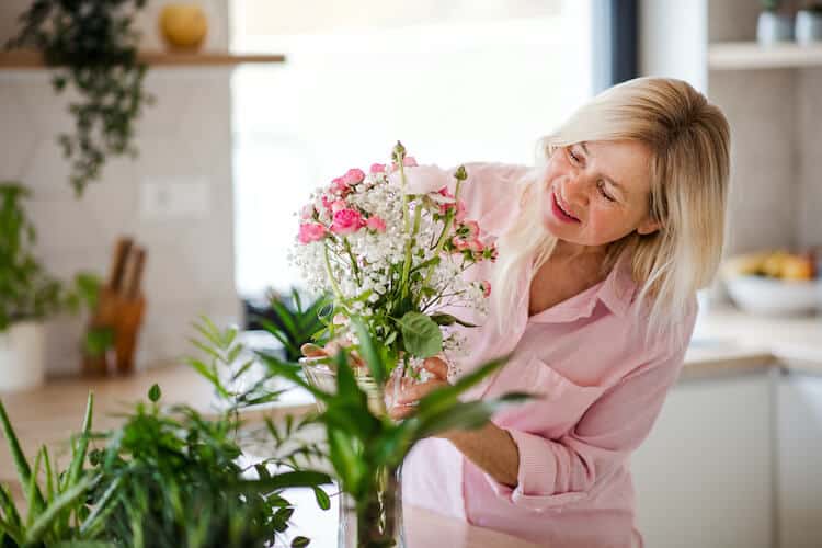 A senior woman arranging flowers for home staging.