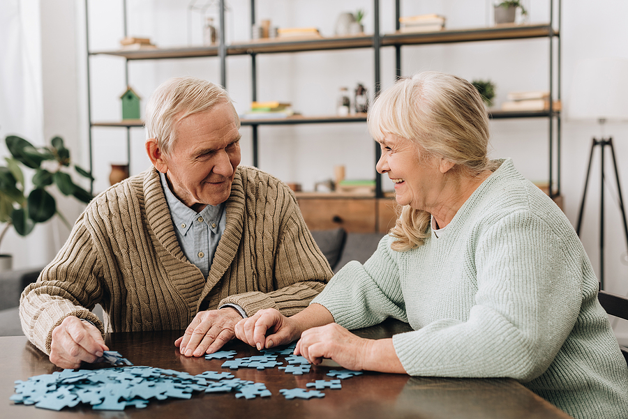 Seniors doing a puzzle and smiling at each other