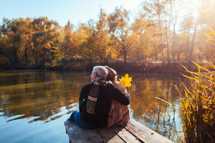 A senior couple sits on a dock, enjoying a mental health break.