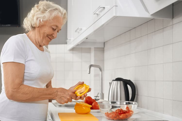 Senior woman cooking healthy meal in celebration of National Nutrition Month.