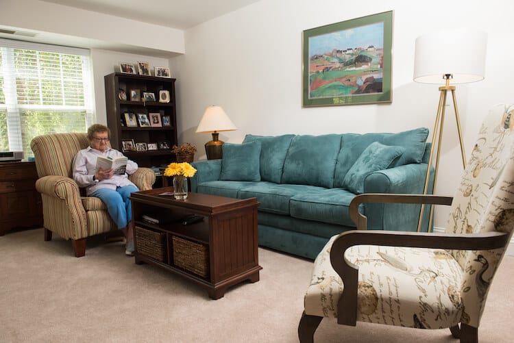 Evelyn Maron in her apartment living room reading a book.