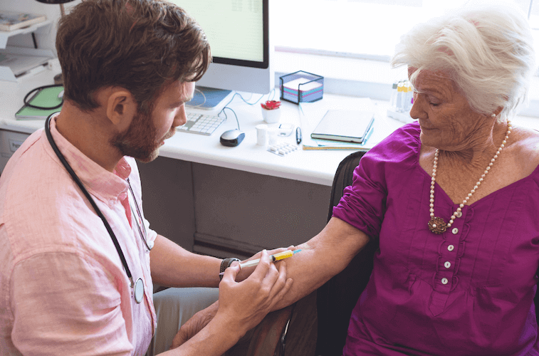 Doctor giving a senior female a vaccine.