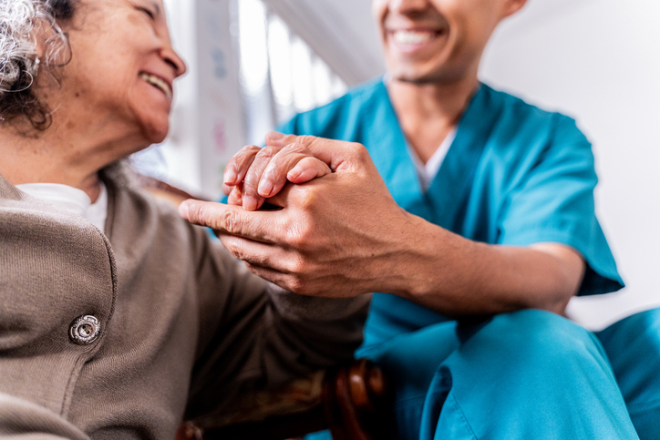 senior woman holding caregivers hand