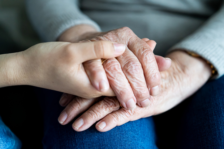 Young hand holding old hands of a woman