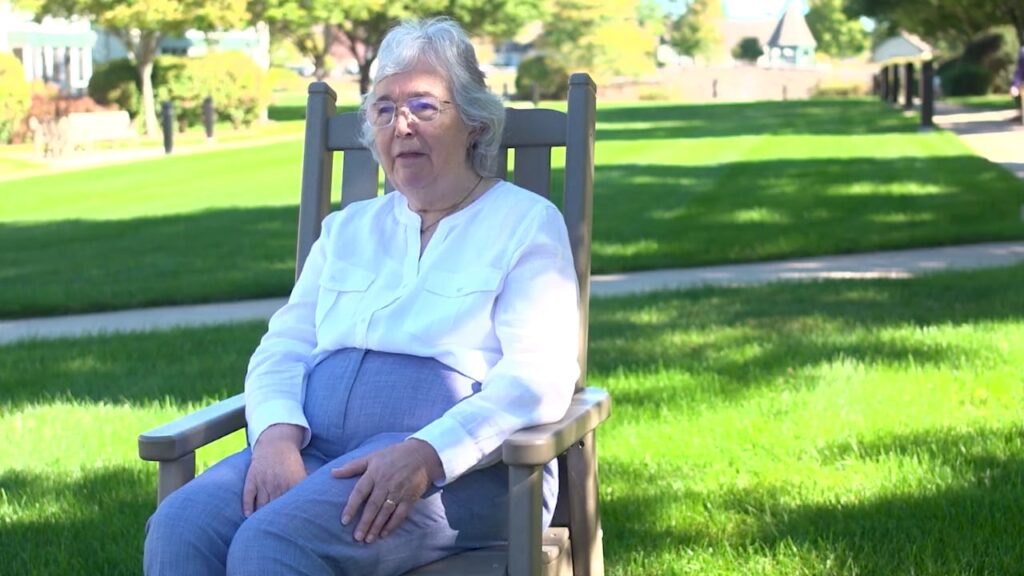 senior lady in high waist pants sitting on chair outside