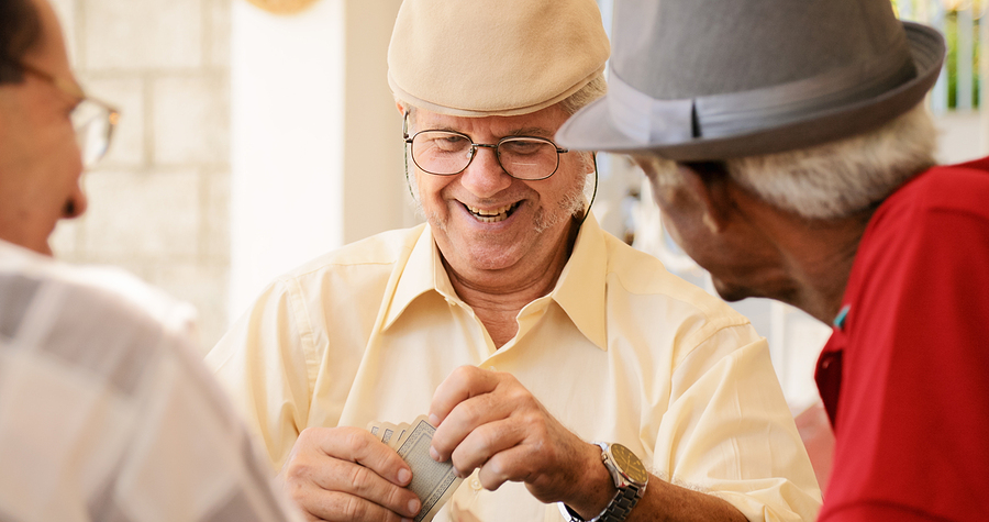 A group of senior men laughing together while playing cards