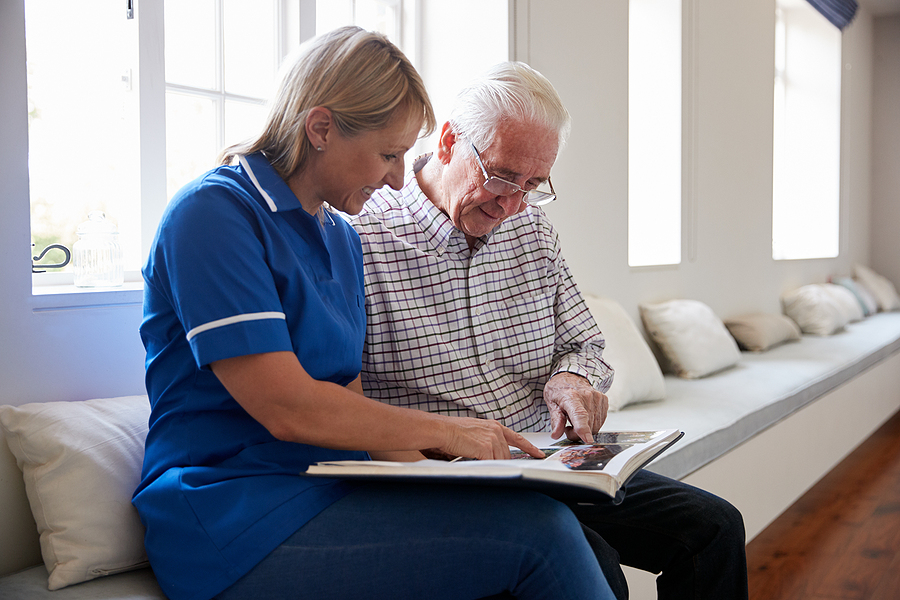 A senior man looks at a photo album with a caregiver.