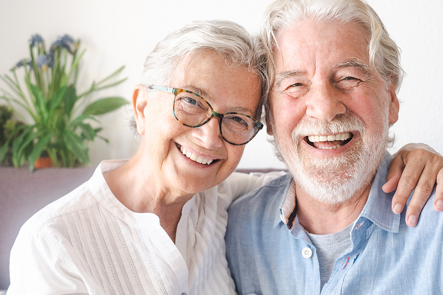 A cheerful senior couple laughing and relaxing in their living room.