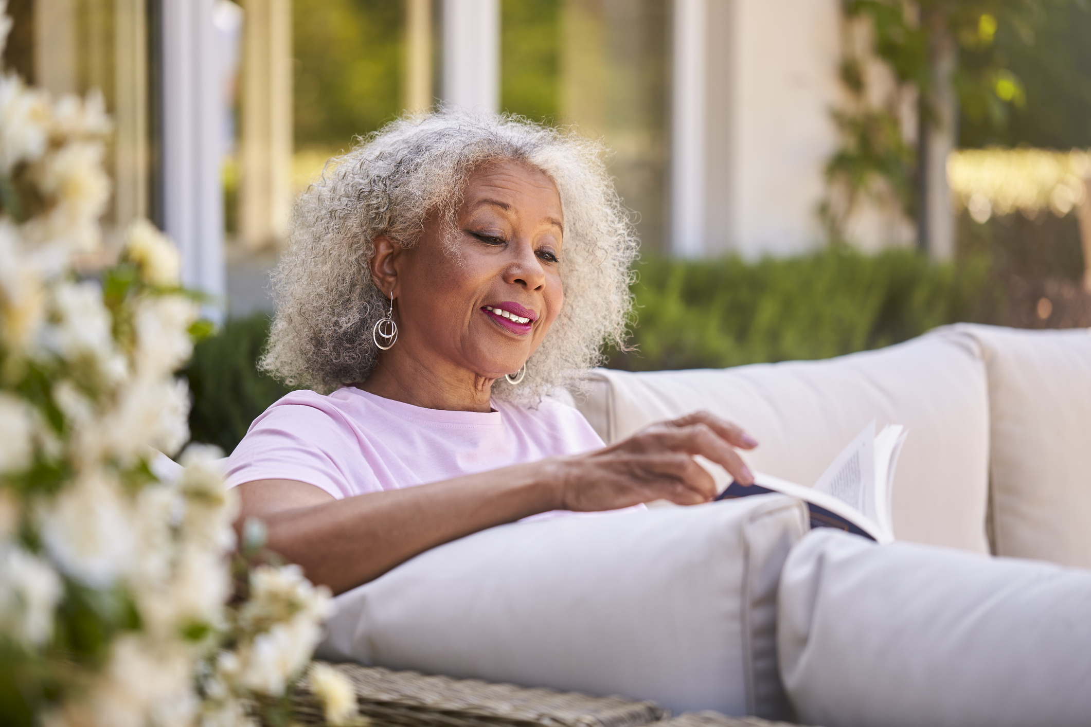 An older woman reads a book outside during the summer